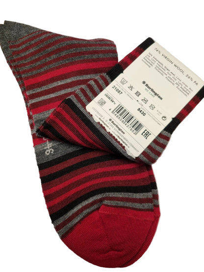 A pair of striped wool socks with red, black, and gray horizontal bands, featuring a solid red toe and heel. A white paper tag with product details is attached to one sock, and the socks are laid flat on a white background.