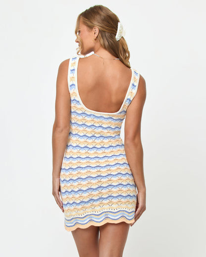 Back view on model of the LSPACE Sunchaser Dress in Daydreamer, a sleeveless crochet mini dress in a blue, peach, and white scallop pattern, showing the scoop back and scalloped hem.